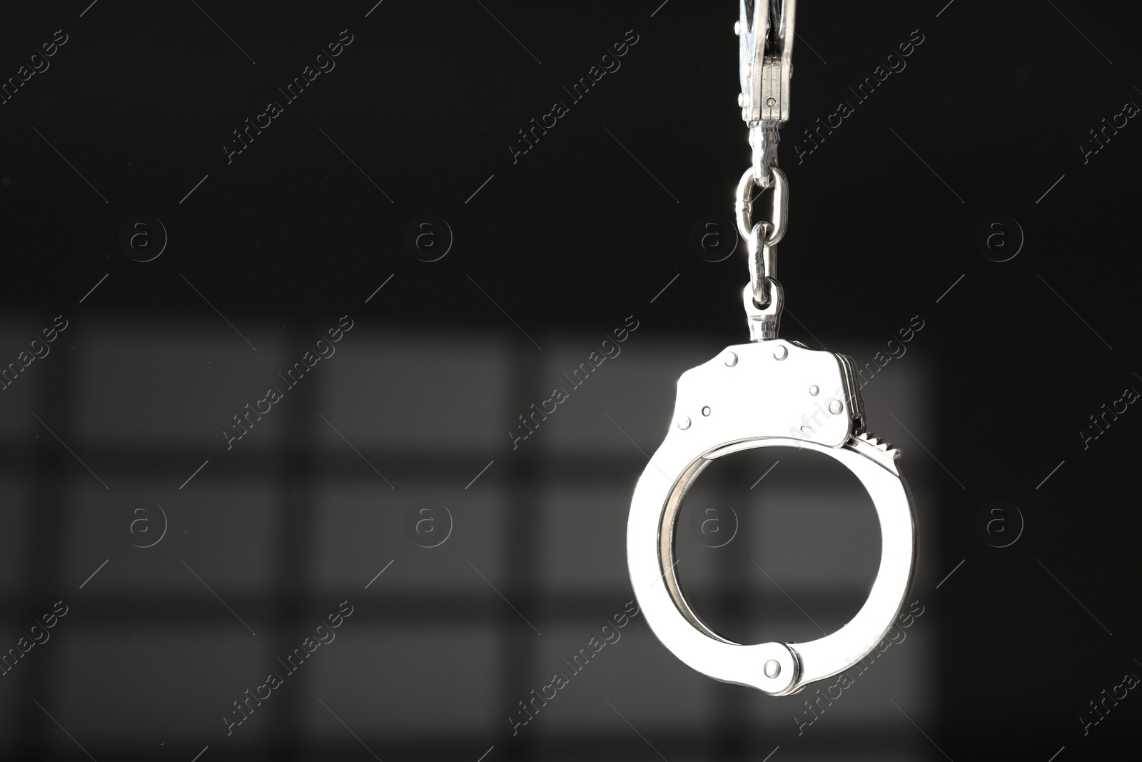 Photo of Metal chain handcuffs on dark background, closeup. Space for text