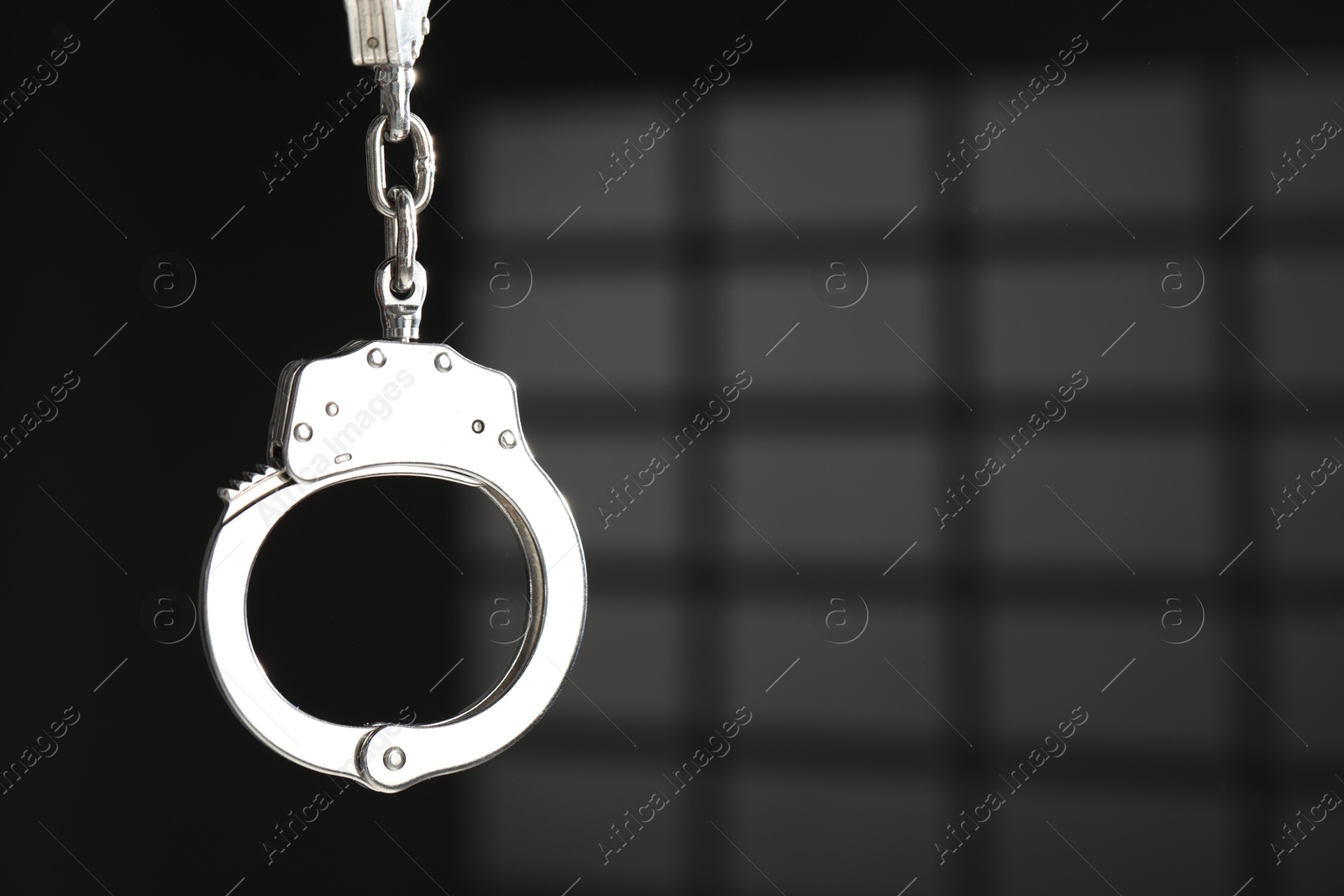 Photo of Metal chain handcuffs on dark background, closeup. Space for text