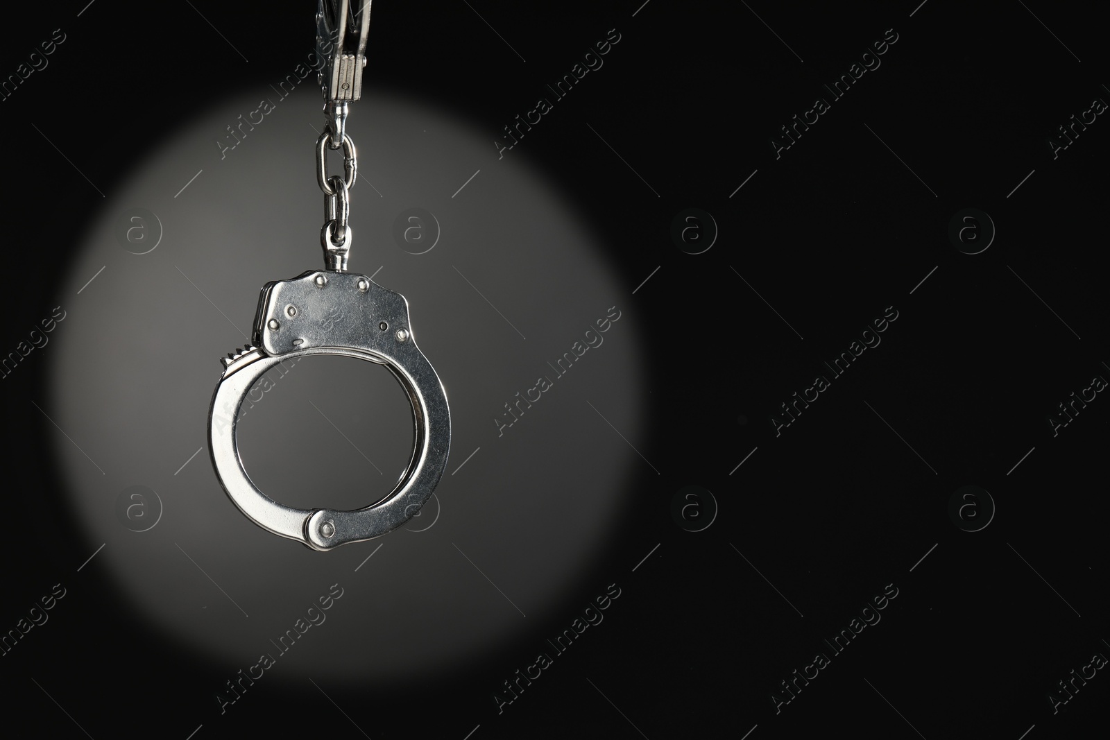 Photo of Metal chain handcuffs on dark background. Space for text