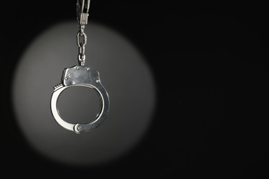 Photo of Metal chain handcuffs on dark background. Space for text