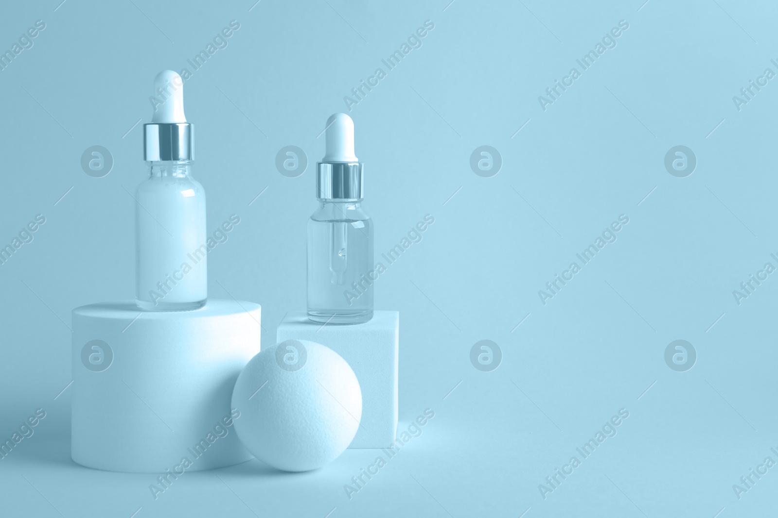 Image of Stylish presentation of cosmetic serum on light blue background, space for text