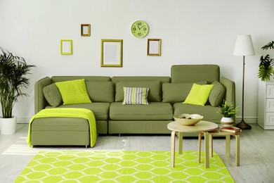 Stylish living room interior. Comfortable olive color couch, nesting tables and decor indoors