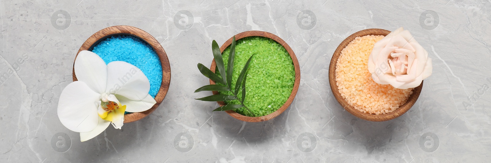 Image of Bowls with different sea salt for spa treatment on grey background, flat lay