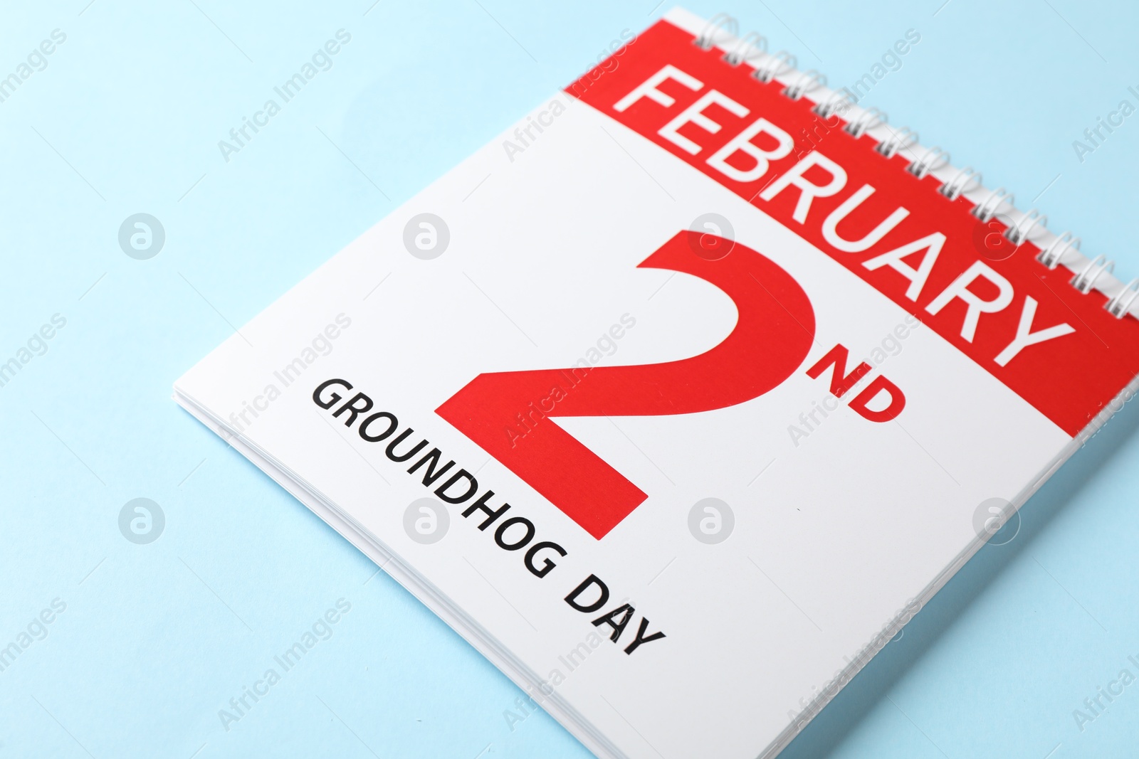 Photo of Calendar with date February 2nd on light blue background, closeup. Groundhog day