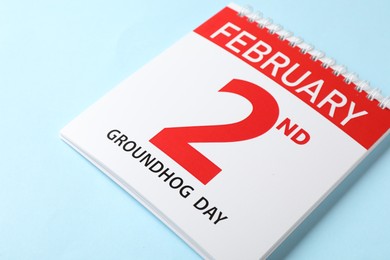 Photo of Calendar with date February 2nd on light blue background, closeup. Groundhog day