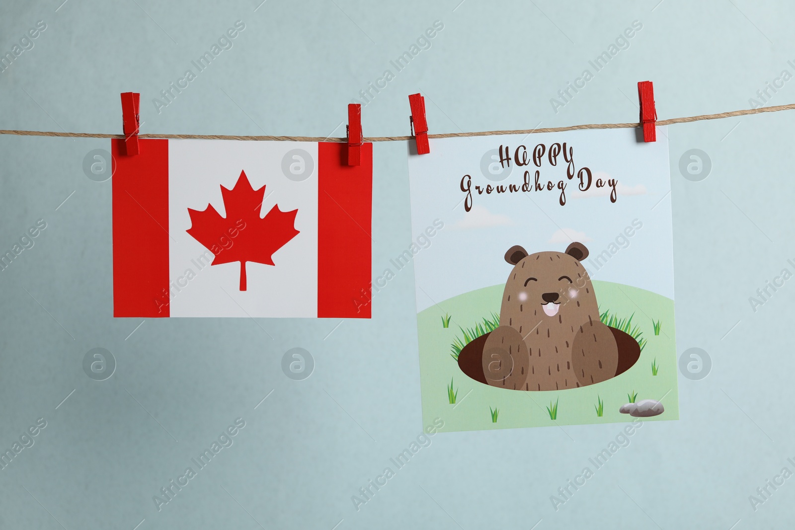 Photo of Happy Groundhog Day greeting card and Canada flag hanging against light background