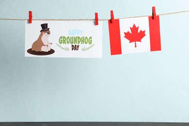 Happy Groundhog Day greeting card and Canada flag hanging against light background, space for text