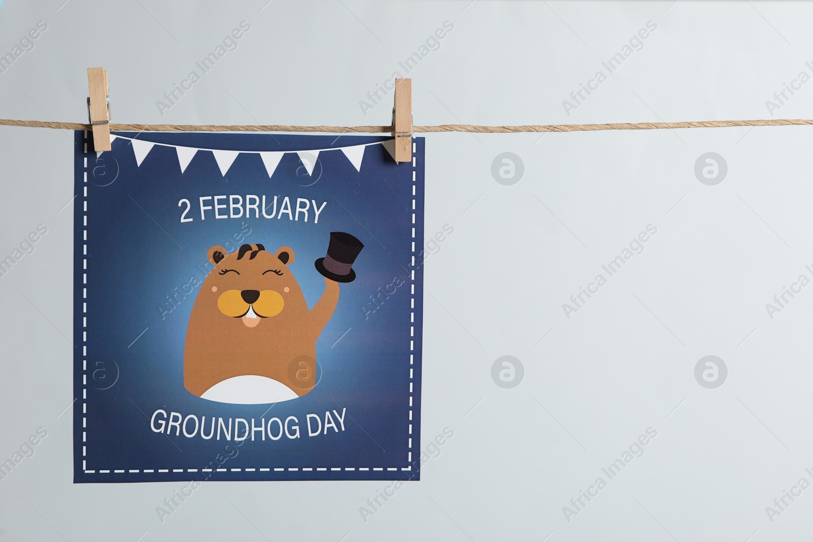 Photo of Happy Groundhog Day greeting card hanging on light background, space for text