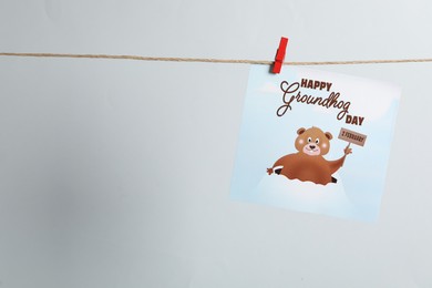 Happy Groundhog Day greeting card hanging on light background, space for text