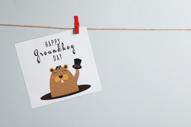 Happy Groundhog Day greeting card hanging on light background, space for text