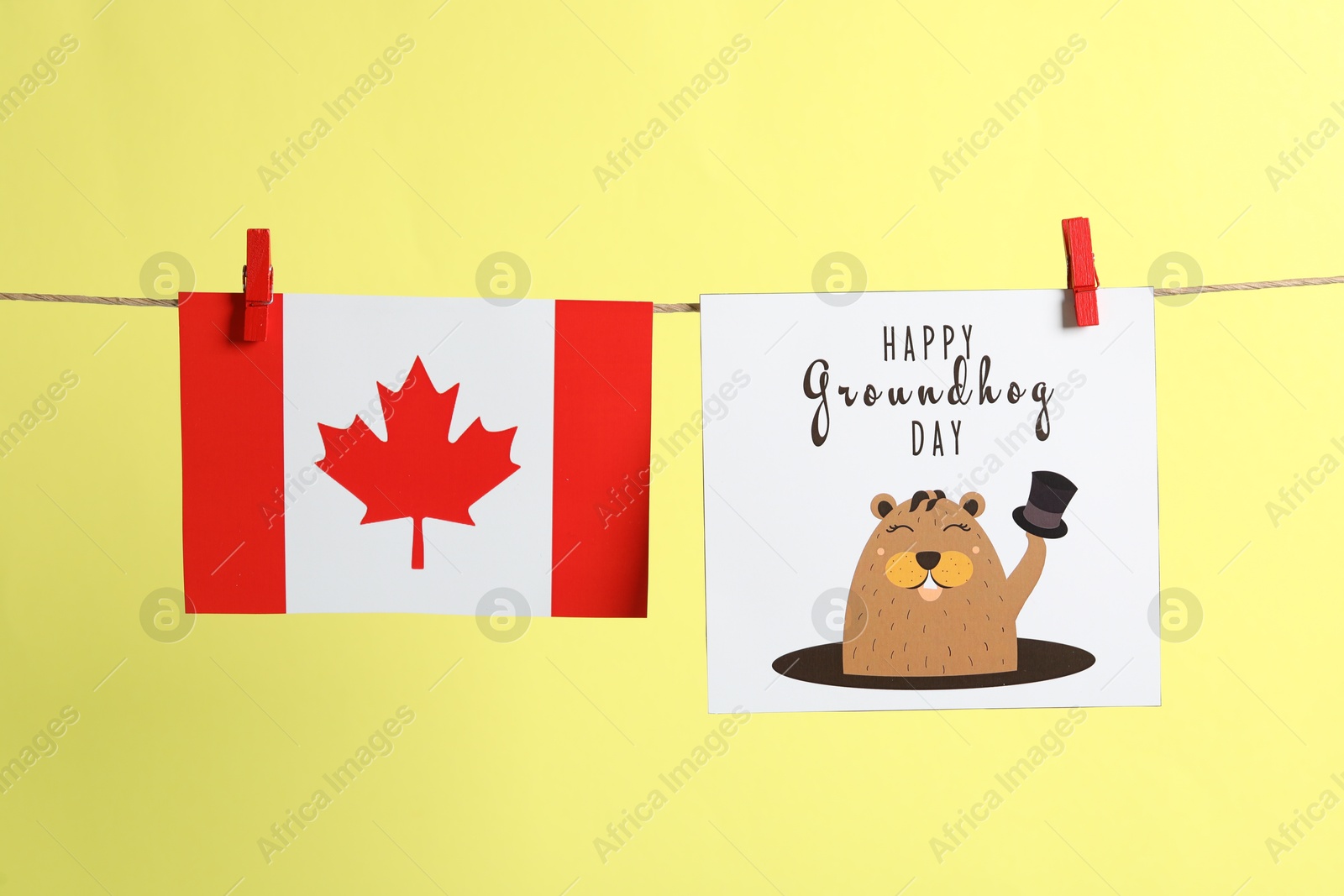 Photo of Happy Groundhog Day greeting card and Canada flag hanging on yellow background