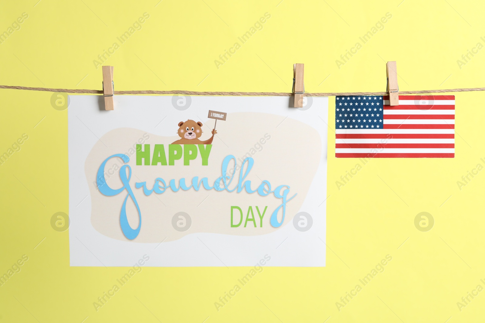 Photo of Happy Groundhog Day greeting card and American flag hanging on yellow background