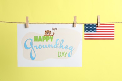 Happy Groundhog Day greeting card and American flag hanging on yellow background