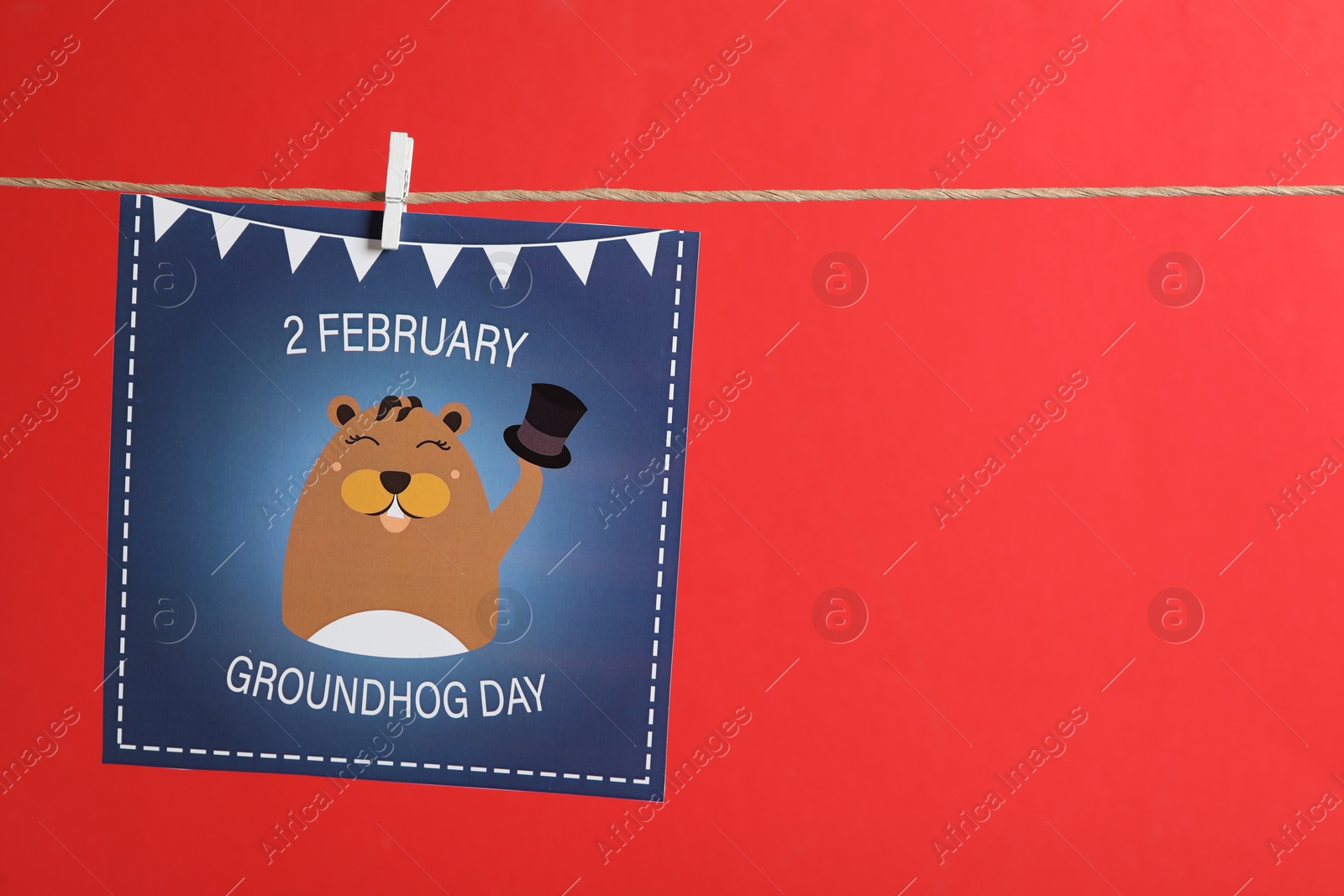 Photo of Happy Groundhog Day greeting card hanging on red background, space for text