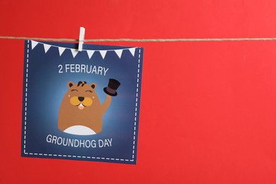 Photo of Happy Groundhog Day greeting card hanging on red background, space for text