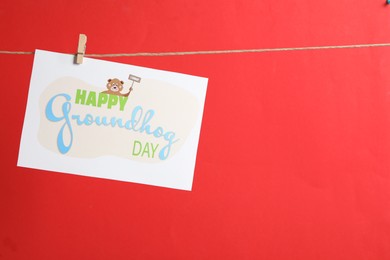 Photo of Happy Groundhog Day greeting card hanging on red background, space for text