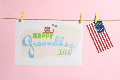 Happy Groundhog Day greeting card and American flag hanging on pink background