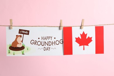 Photo of Happy Groundhog Day greeting card and Canada flag hanging on pink background