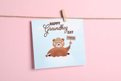 Photo of Happy Groundhog Day greeting card hanging on pink background