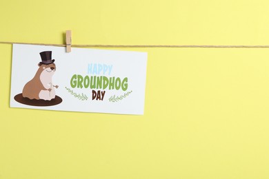 Happy Groundhog Day greeting card hanging on yellow background, space for text