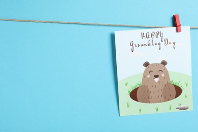 Happy Groundhog Day greeting card hanging on light blue background, space for text