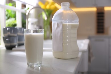 Photo of Gallon bottle of milk and glass on white countertop in kitchen