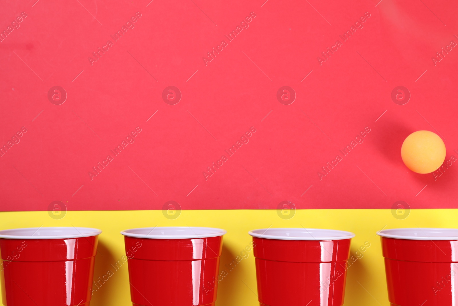 Photo of Plastic cups and ball on color background, flat lay with space for text. Beer pong game