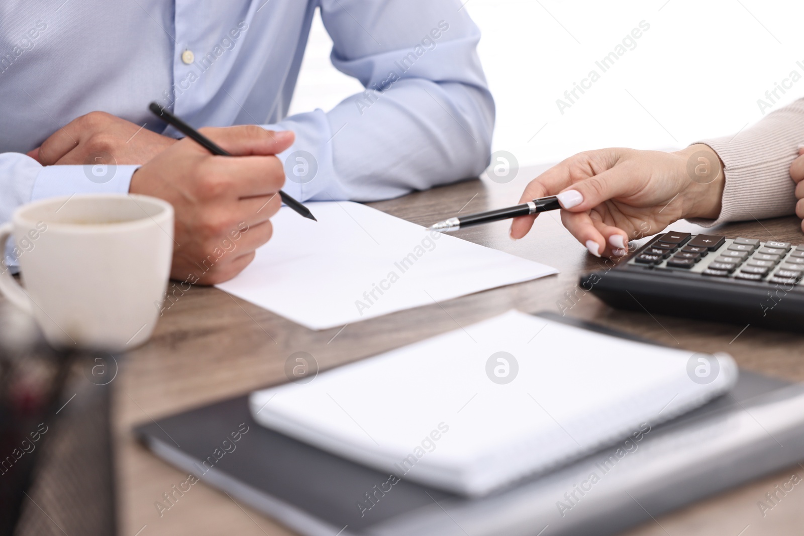 Photo of Banker working with client at wooden table in office, closeup