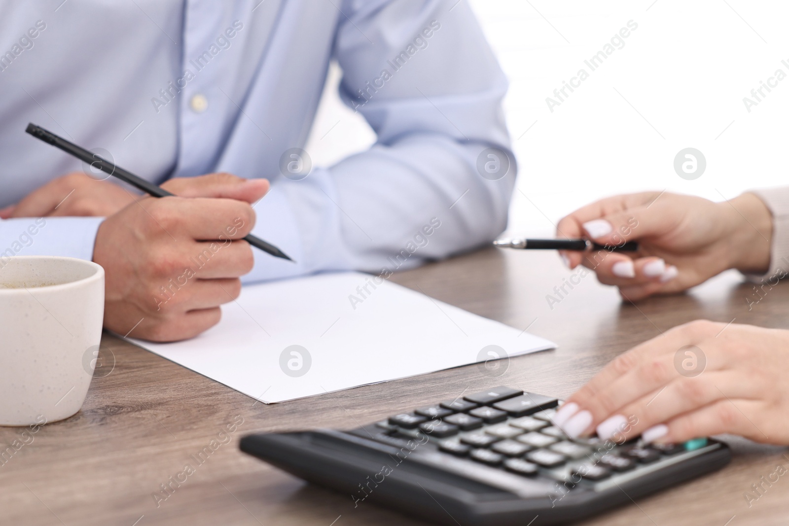 Photo of Banker working with client at wooden table in office, closeup