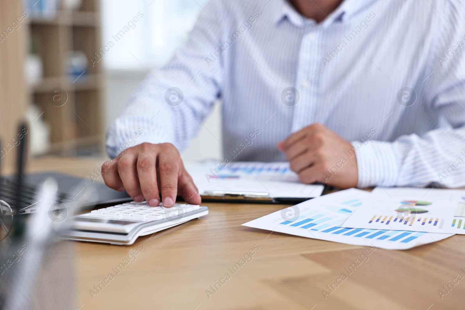 Photo of Banker using calculator at wooden table in office, closeup