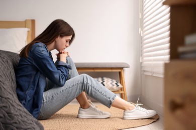 Photo of Loneliness concept. Sad teenage girl on floor at home