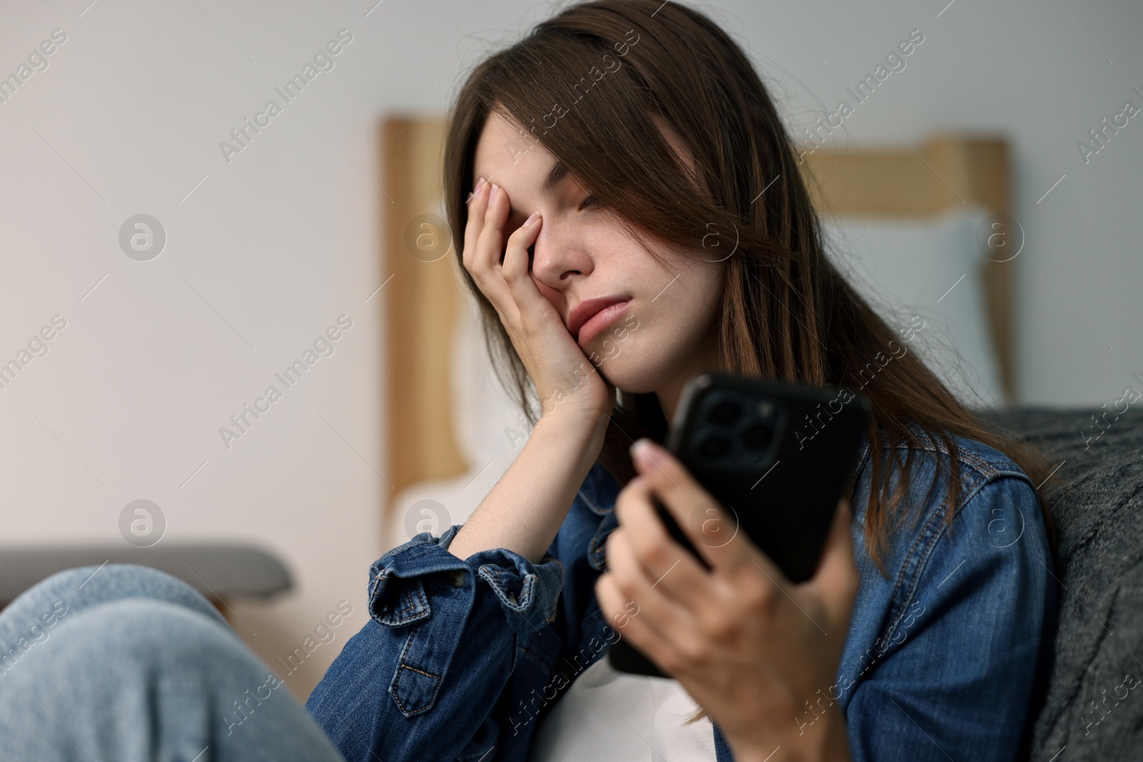 Photo of Loneliness concept. Sad teenage girl with smartphone at home