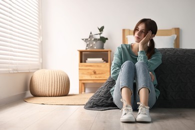 Photo of Loneliness concept. Sad teenage girl on floor at home, space for text