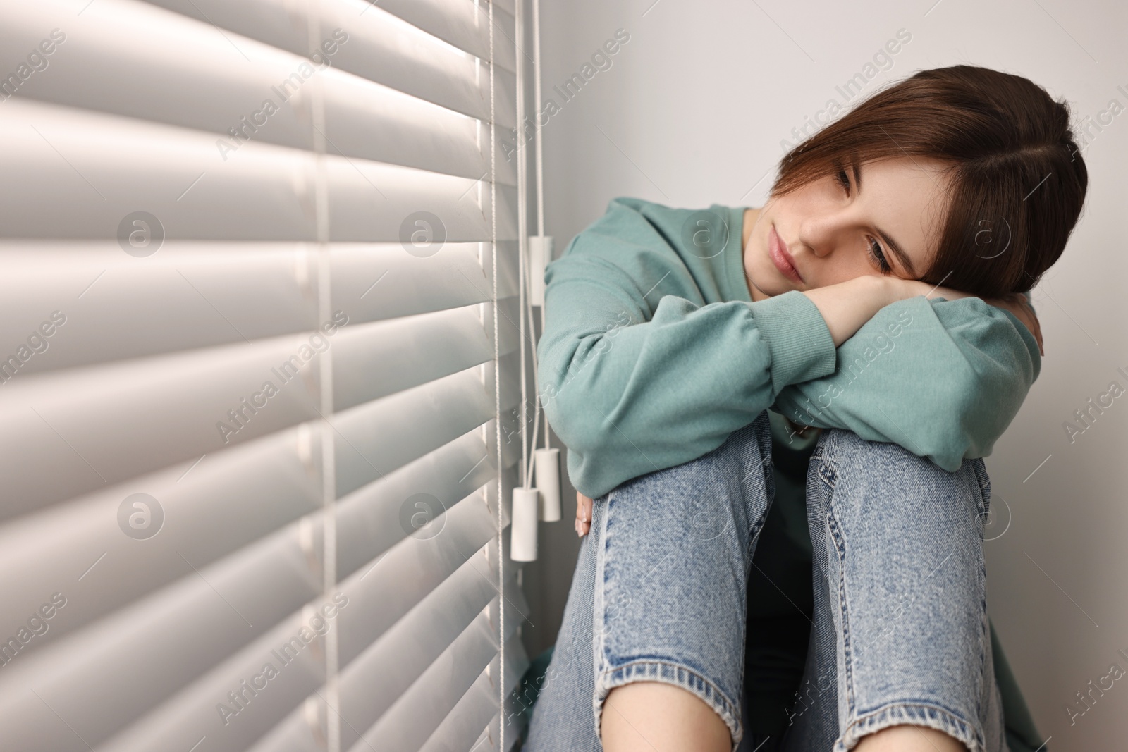 Photo of Loneliness concept. Sad teenage girl near window at home