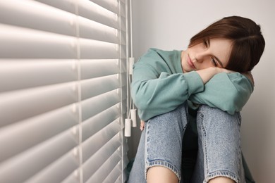 Loneliness concept. Sad teenage girl near window at home