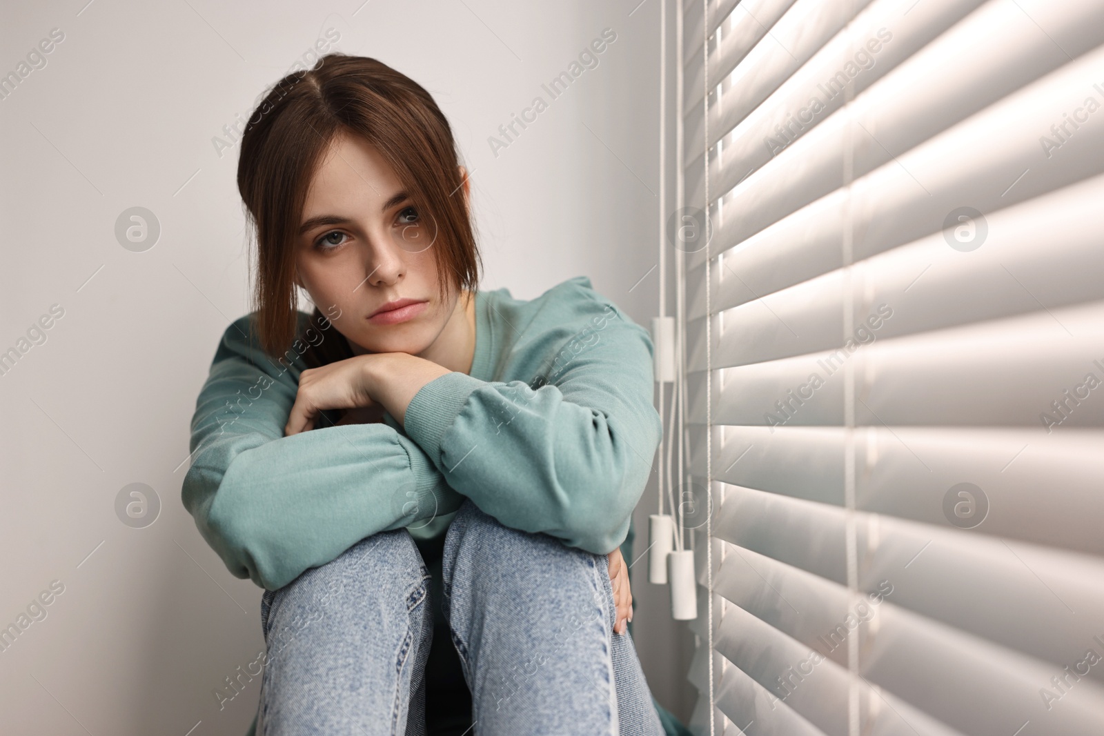 Photo of Loneliness concept. Sad teenage girl near window at home