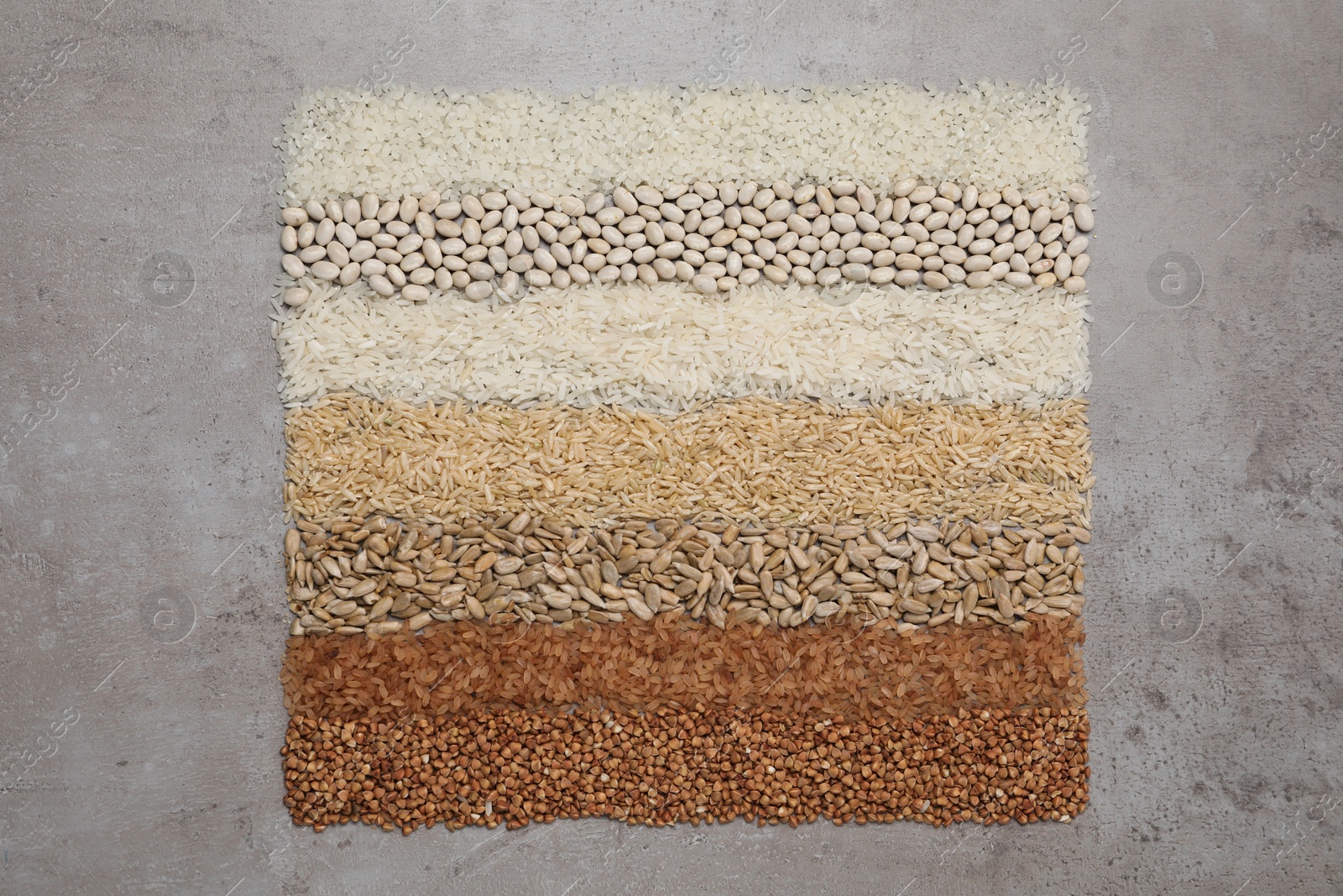 Photo of Different types of cereals, legumes and seeds on grey textured table, flat lay