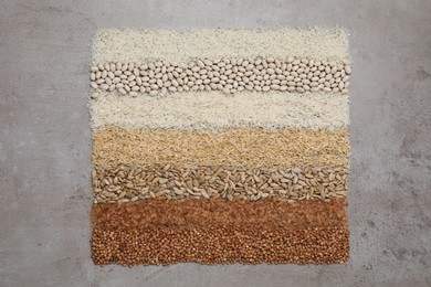 Photo of Different types of cereals, legumes and seeds on grey textured table, flat lay