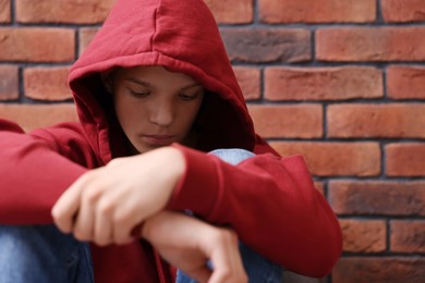 Loneliness concept. Sad teenage boy near brick wall