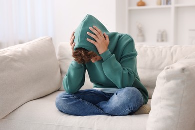 Loneliness concept. Sad teenage boy on sofa at home