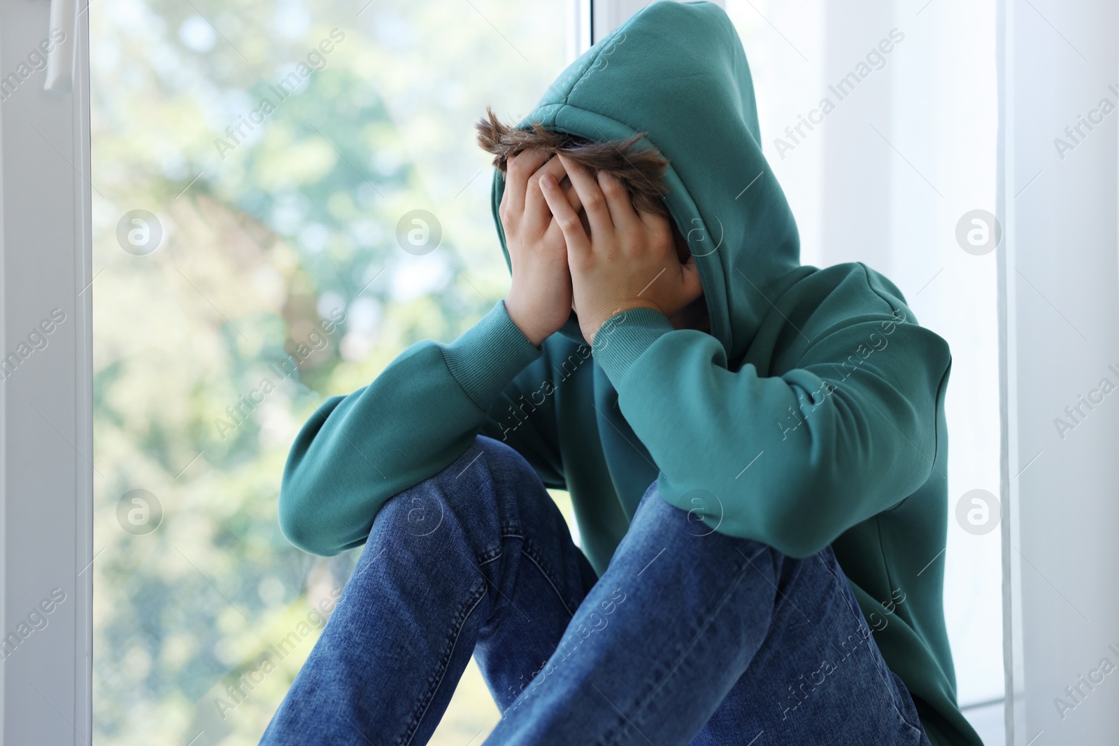 Photo of Loneliness concept. Sad teenage boy near window indoors