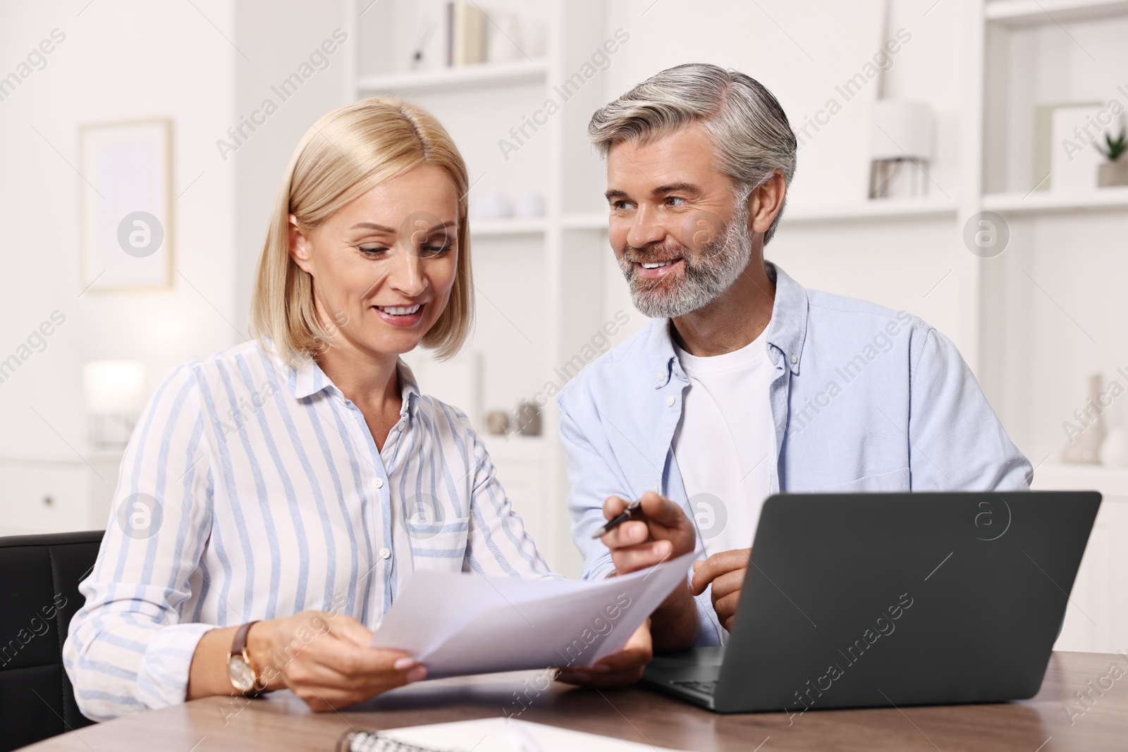 Photo of Pension savings. Couple planning budget at table indoors