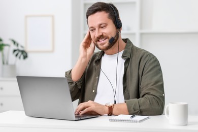 Interpreter in headset having video chat via laptop at white table indoors