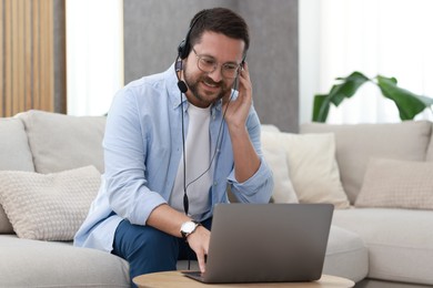 Interpreter in headset having video chat via laptop at wooden table indoors