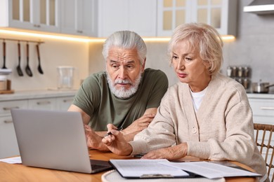 Photo of Pension savings. Senior couple planning budget at wooden table indoors