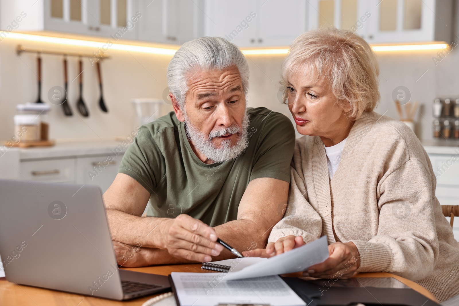 Photo of Pension savings. Senior couple planning budget at wooden table indoors