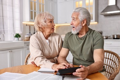 Photo of Pension savings. Senior couple planning budget at wooden table indoors