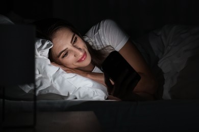 Bad habit. Young woman using smartphone in bed at night