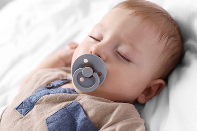 Cute little baby with pacifier sleeping on bed at home