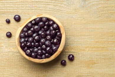 Photo of Ripe acai berries in bowl on wooden table, top view. Space for text